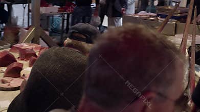 Seller in a red apron cuts swordfish, cleans insides. Old fish market in Catania