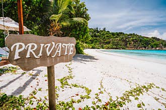 Private sign at tropical sandy beach with blue ocean lagoon in background at Mahe island, Seychelles