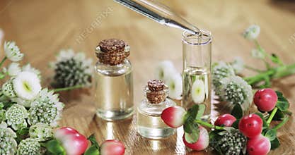 Perfumer making aroma perfume pouring essential oil pipette to glass bottle.