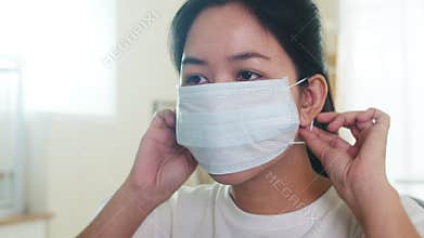 Depressed Asian business woman wearing protective mask sitting on sofa in living room at house when social distancing stay at home