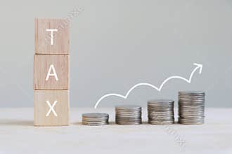 The letter `TAX` on a wooden cube and coins are arranged in a bar graph with growing arrow symbol.