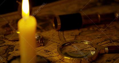 exploration concept - antique objects on old world map in candlelight
