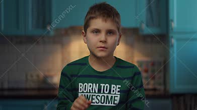 Autistic boy gesticulating with hands standing at the kitchen in slow motion. Happy child with autism at home. Autism