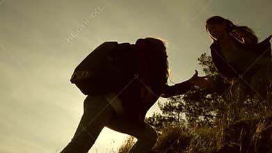 Climbing the mountain in search of adventure. free women travelers climb mountain, offer each other a helping hand