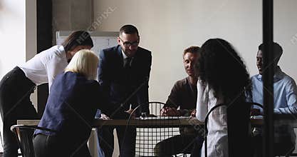 Smiling diverse employees brainstorming at modern workplace.