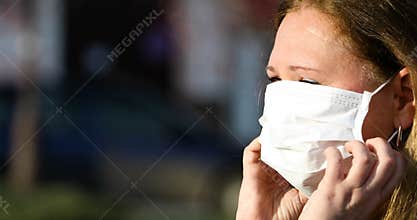 Woman puts on a mask for protection against coronavirus COVID-19.