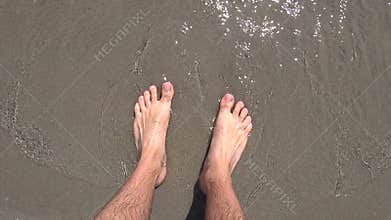 Bare feet of man on the beach of Adriatic sea, washing by water
