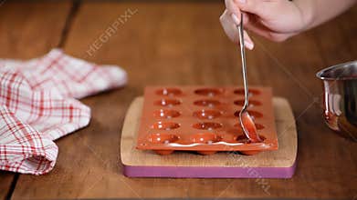 The confectioner fills the silicone mold with strawberry puree. Making strawberry jelly.