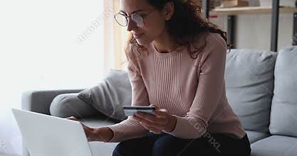 Happy female customer holding credit card paying online on laptop