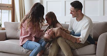 Happy young married couple having fun with small daughters.