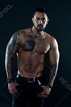 Jewelry for real men. Bearded man with tattooed torso. Macho sexy bare torso. Fit model with tattoo art skin. Sportsman