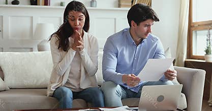 Frustrated young couple stressed about high mortgage rates doing paperwork