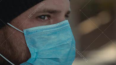 Close up man's face in a medical mask for protection against flu or coronavirus outdoor. Corona virus pandemic. Epidemic viral
