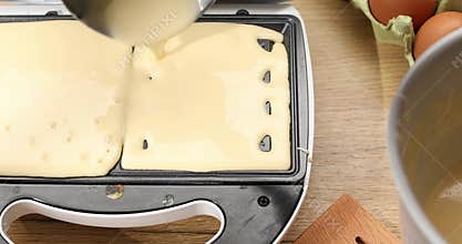 Liquid dough poured waffle iron machine to prepare Belgian waffle.