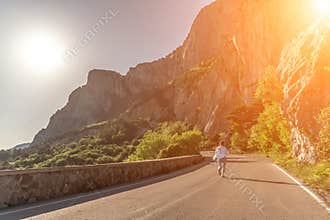 woman running mountain. Happy woman runs along an asphalt road in the middle of a mountainous area. She is dressed in