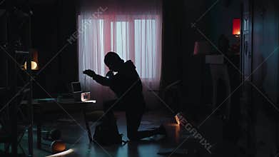 A thief in a black balaclava commits a burglary, stealing cash and valuables. The robber runs away, illuminated by the