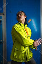 an Asian man in a green jacket is posing in front of a blue door