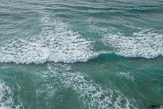 Ocean foamy waves approaching rocky shore. Top view