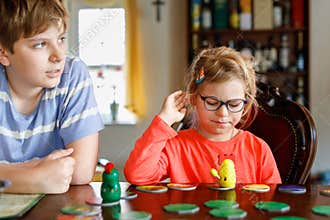 Family playing board game at home. Kids play strategic game. Little sister girl and school brother boy. Fun indoor