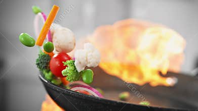 Tossing Vegetarian Food with Mushrooms and Edamame in a Skillet when Stir Frying on Burning Fire in Slow Motion