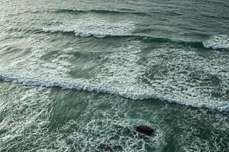 Ocean foamy waves approaching rocky shore. Top view