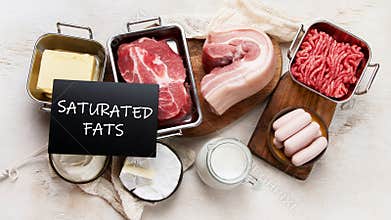Saturated fats on tables. Raw meat, sausages, cheese, butter. Bad food concept