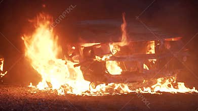 Cinematic film shot of a vehicle burning in flames after a car crash at night.