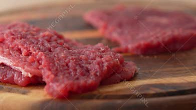 Beating raw meat on a wooden board.