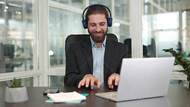 Worker in wireless headphones pretending to playing invisible piano at workplace