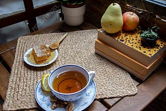 Morning setup on wooden table at balcony for morning relaxation with books, cup of tea, teapot, organic honey, green tea leaves