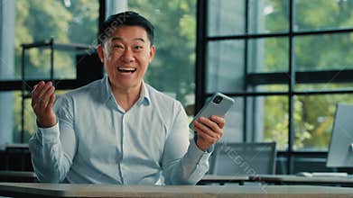 Surprised Asian successful businessman emotional man professional winner receive good message on mobile phone feel shock