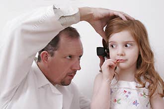 Doctor looking in little girl's ear