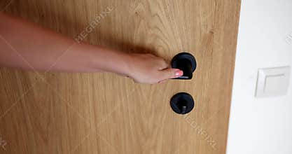 Woman hand opens wooden door in room closeup