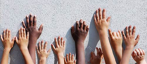 Children's hands leaning against a wall