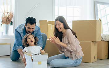 Happy family with three members Caucasian father, Asian mother and little daughter laughing, playing together to put the girl in