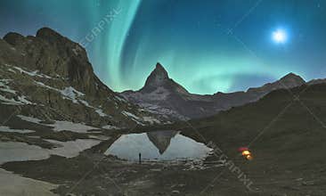 Mountaineer stands in front of the lake where Aurora Borealis showing his best show, Matterhorn area. Switzerland