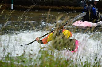 Kayaker Paddling Through Rapids Behind Tall River Grass
