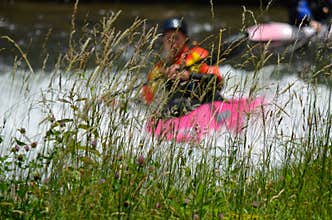 Title: Kayaker Paddling Through Rapids Behind Tall River Grass