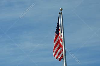 American Flag Waving on Flagpole Against Blue Sky