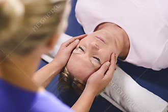 Young therapist doing reiki to senior woman