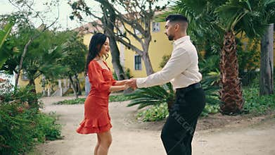 Beautiful couple practicing samba in garden. Performers dancing latino style.