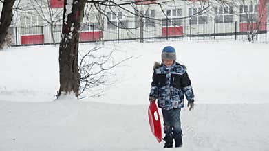 Happy boy with his plastic sleds, enjoying the snow and winter activities. Ideal for showcasing outdoor fun and play.