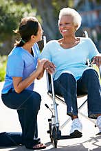 Carer Pushing Senior Woman In Wheelchair