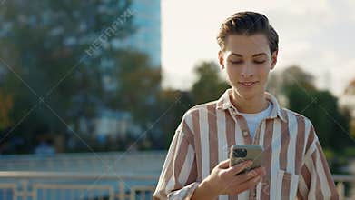 Young Man Walking on the Street Using His Smartphone, Texting with Friends. Smile Internet Face Technology Texting