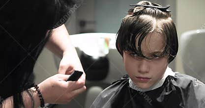 Barbeshopper cuts the bangs of a disgruntled boy.