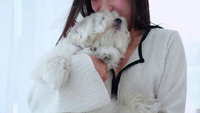 Young asian woman standing carrying with fluffy dog shih tzu with love in living room at home.