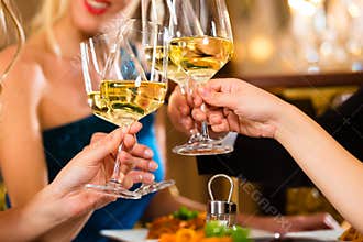 Friends in a very good restaurant clink glasses