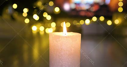 Christmas candle burning in front of the fireplace in atmospheric lights