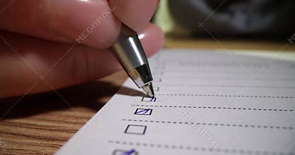 Closeup of hand checking or ticking blue pen on checklist checkbox and to-do list