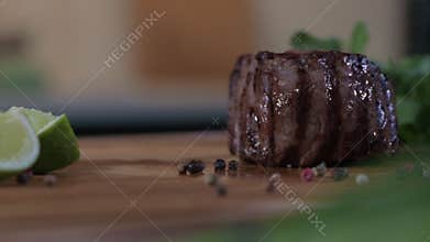 chef puts juicy fresh beef filet mignon steaks on wooden tray with lime slices